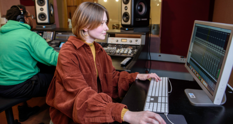 female and male student in recording studio adjusting sound