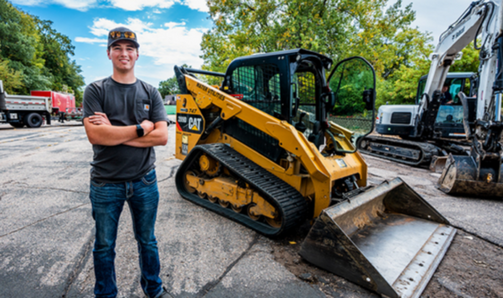 young man standing on a street in front of equipment to fix the road