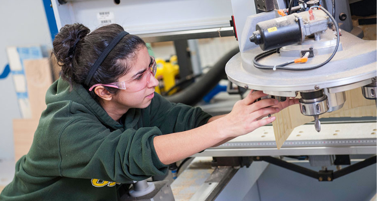 female student adjusting saw in wood shop