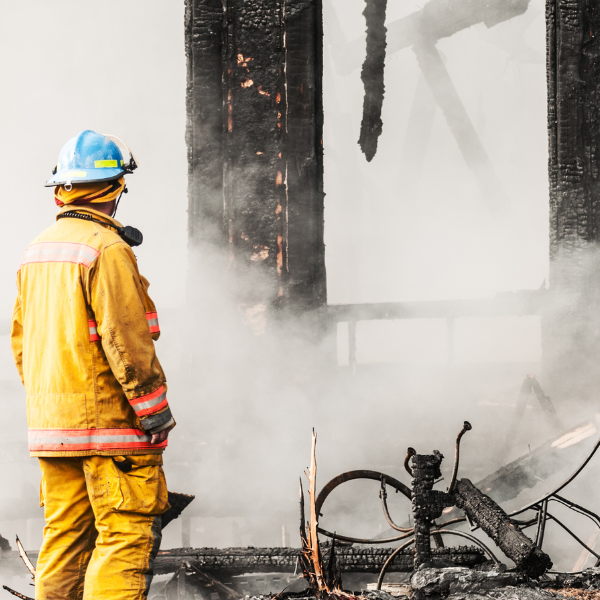 firefighter students in fire gear with a hose putting out a fire