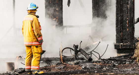 fire fighter in uniform holding fire hose standing next to a fire truck