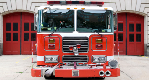 fire fighter in uniform holding fire hose standing next to a fire truck