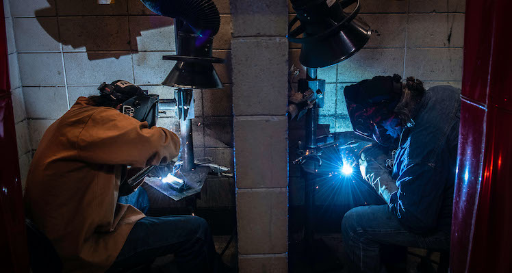 Two students welding projects in classroom lab