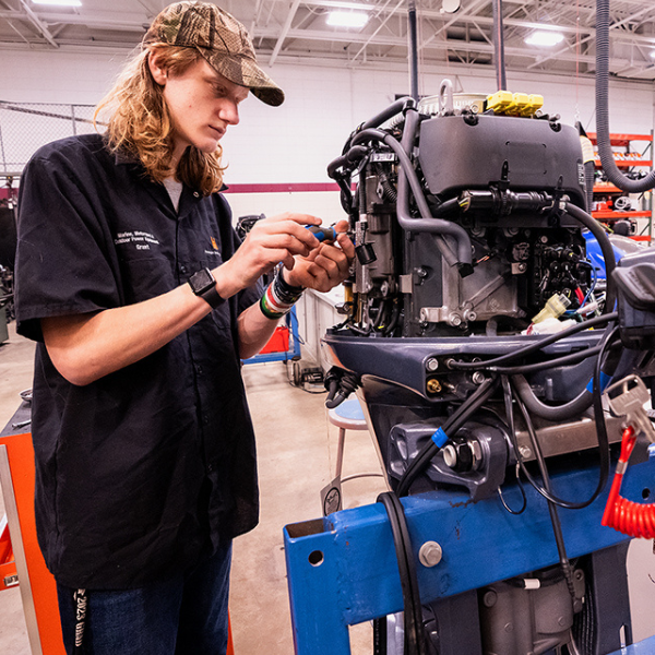 Worker inspecting or tightening lug nuts on a large truck wheel.