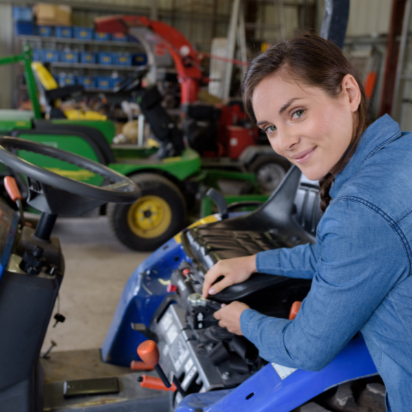 Worker inspecting or tightening lug nuts on a large truck wheel.
