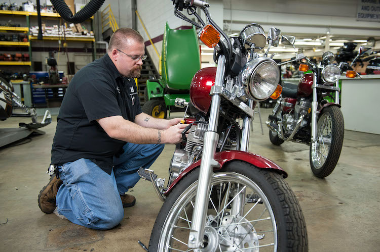 man performing mechanical work on a motorcycle