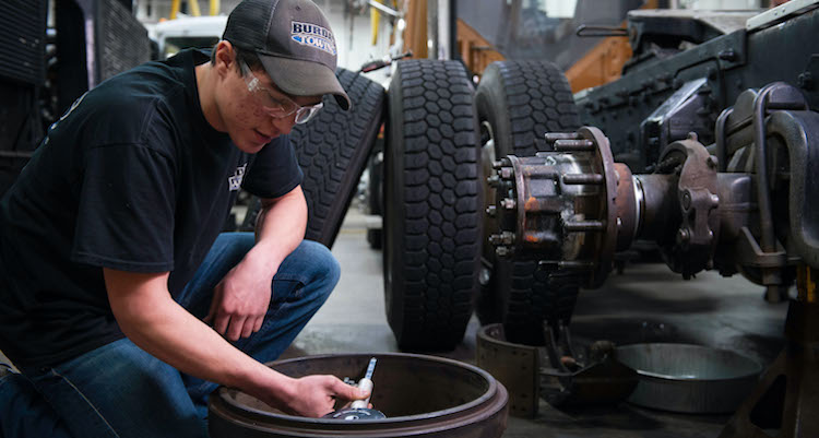 Male working on a large truck tire in garage