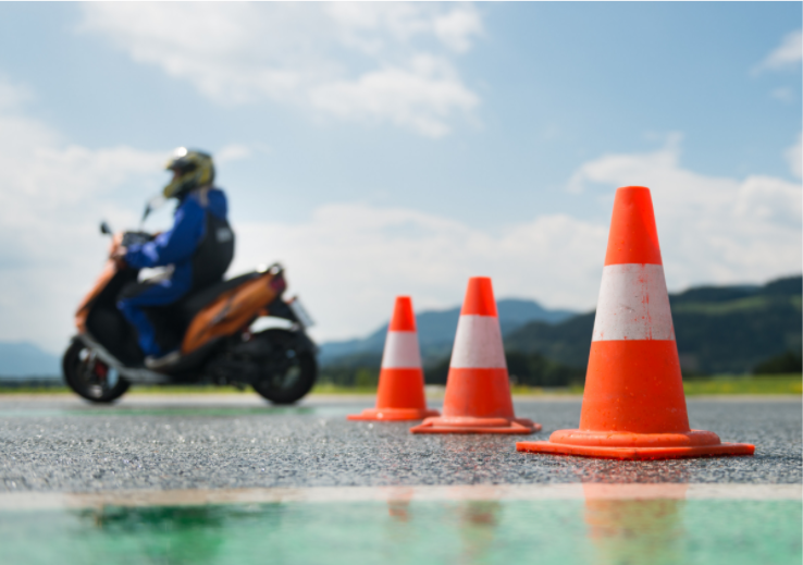person on motorcycle driving through orange cones in parking lot