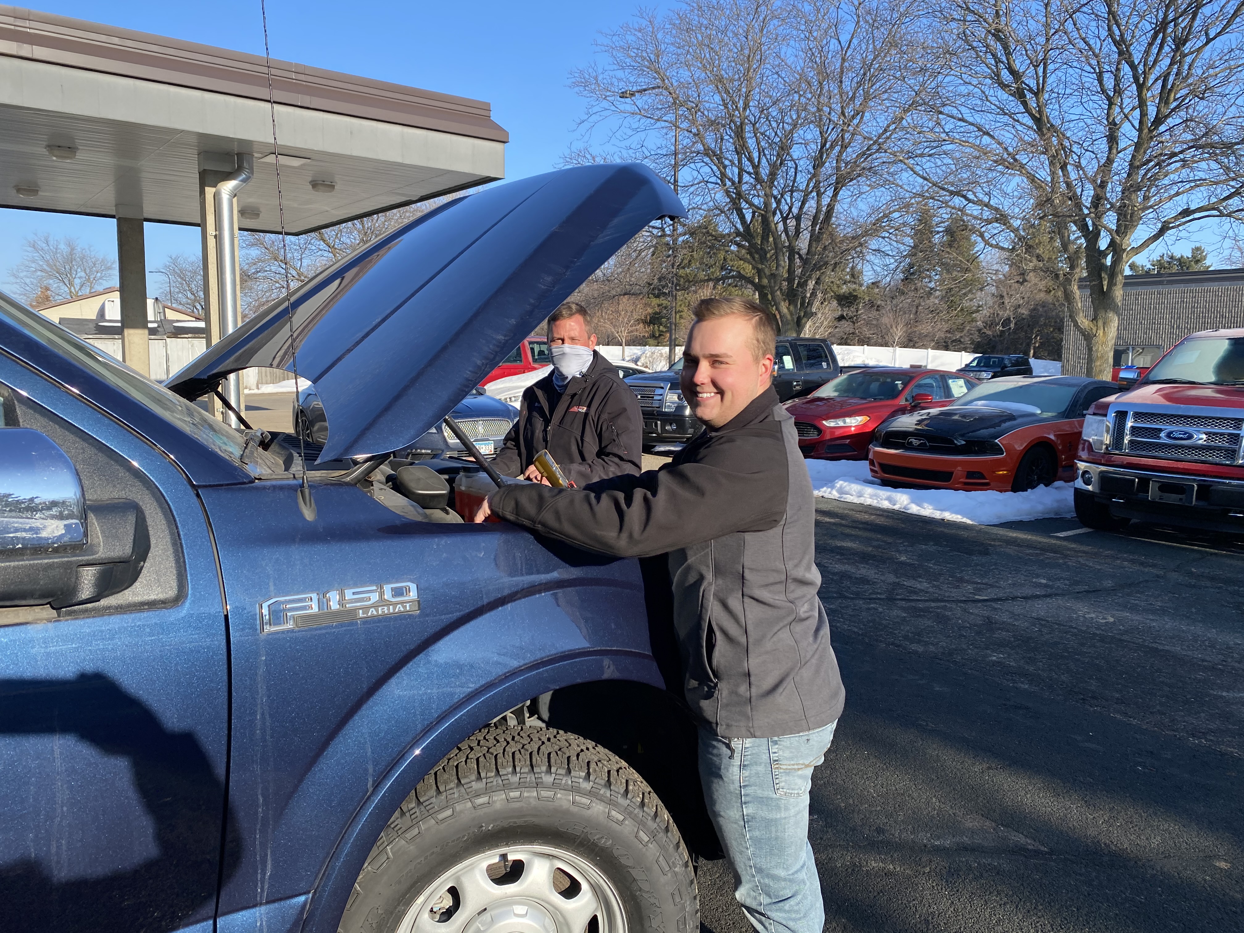 Tyler Carmody and man work on Ford F-150 truck in parking lot