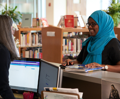 student in library checking out material